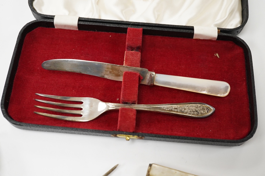 A small quantity of assorted small silver and plated flatware, a small silver stand, a silver napkin ring and a pair of modern silver mounted dwarf candlesticks.